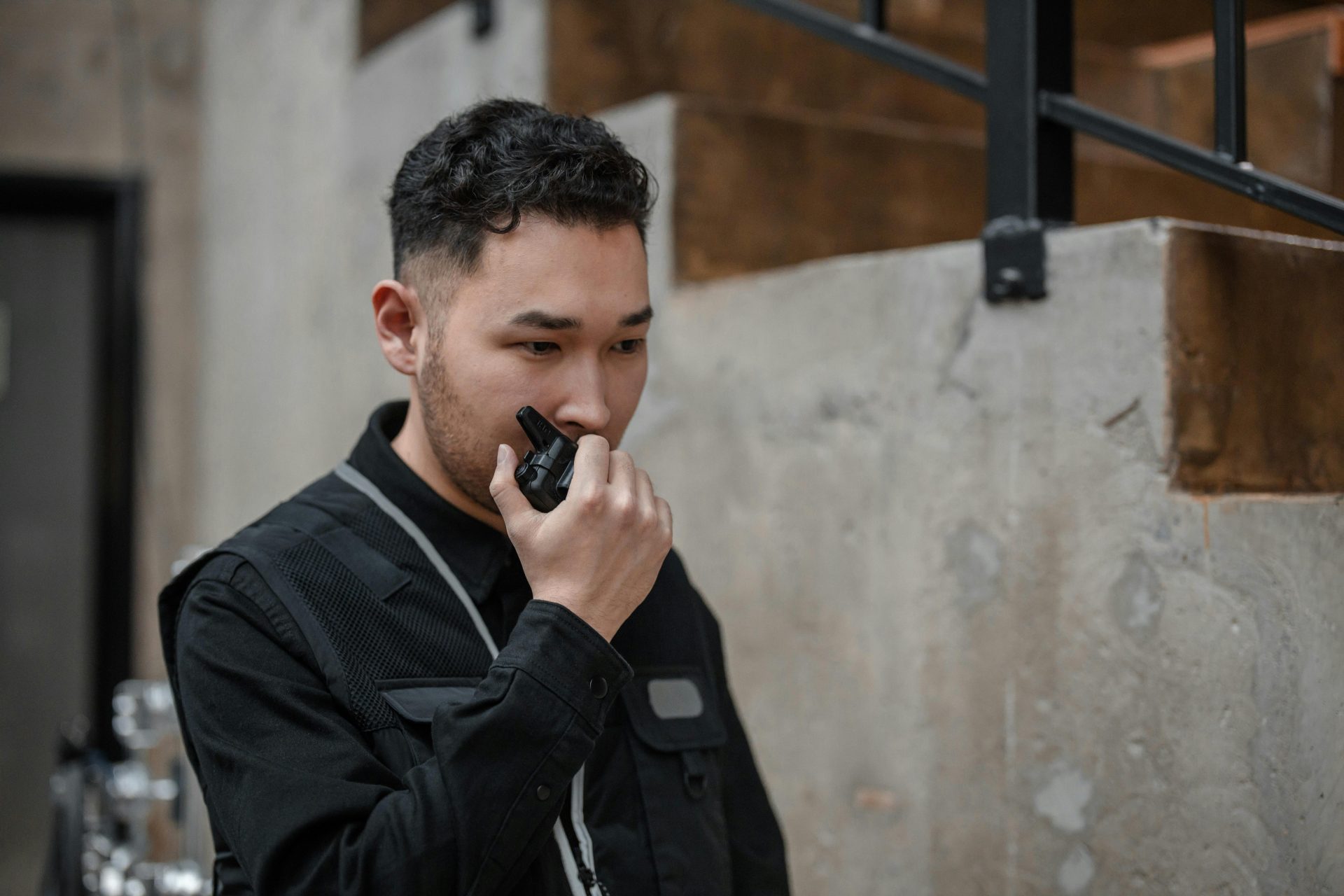 Asiatischer Sicherheitsbeamter verwendet in einem Innenbereich ein Walkie-Talkie und demonstriert so Kommunikation und Wachsamkeit.